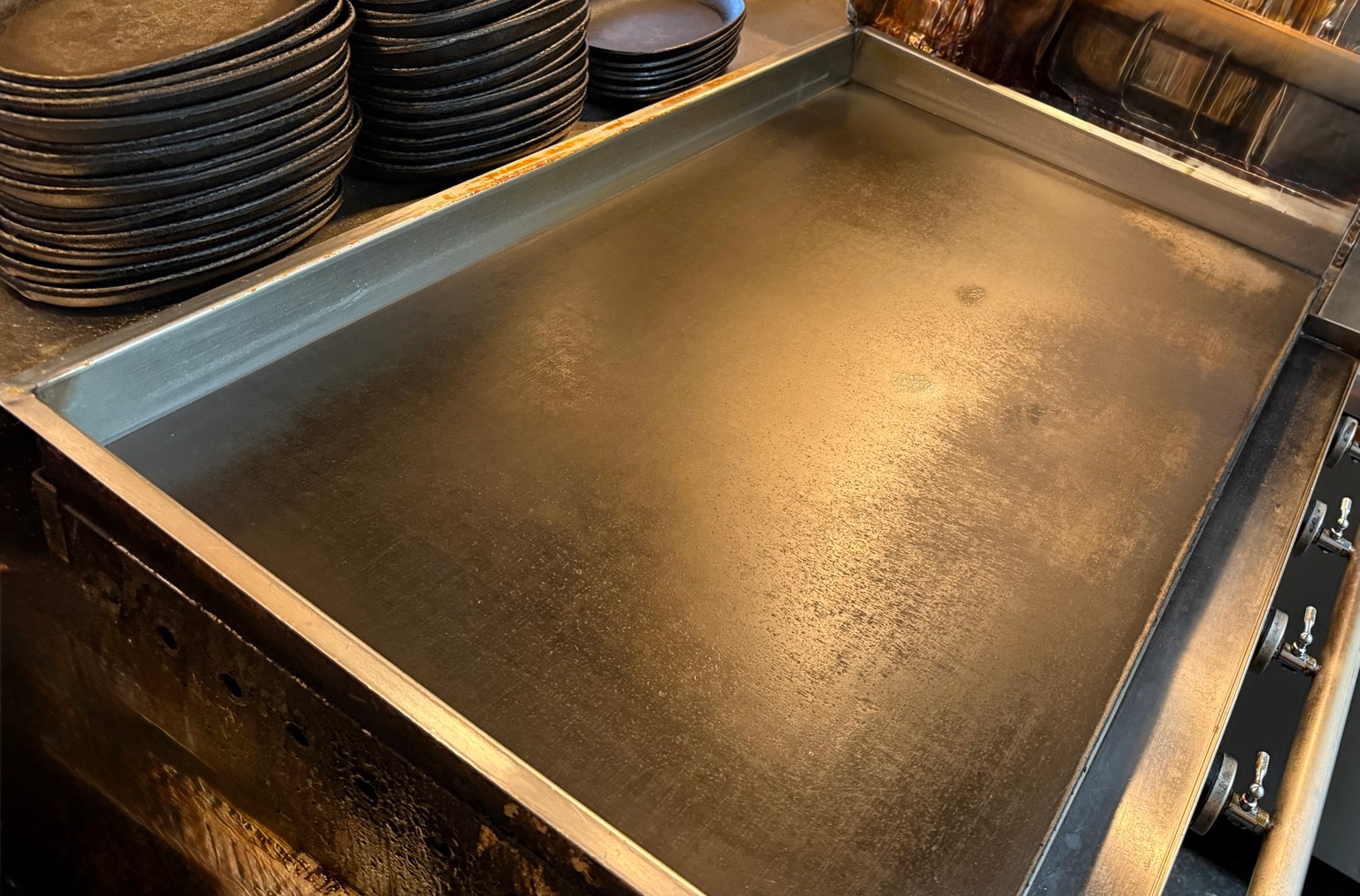 鉄焼の鉄板と、料理を迎える黒い皿
